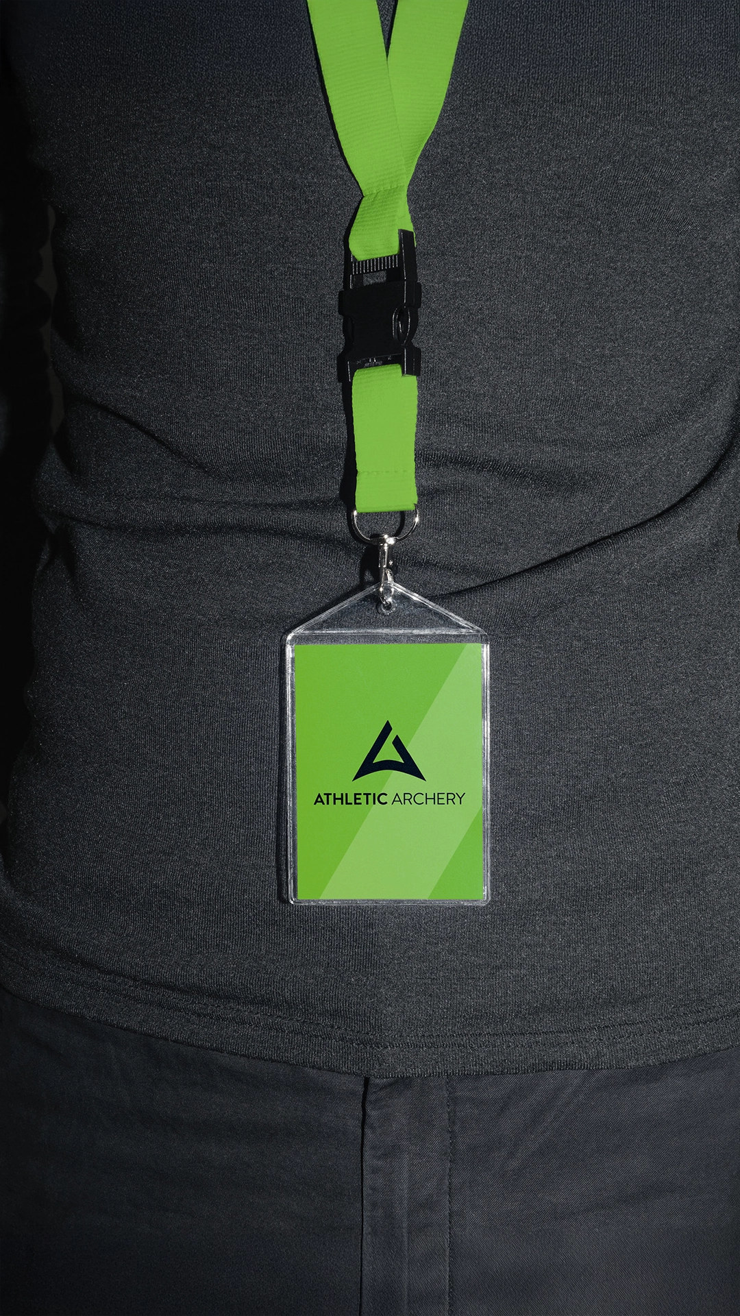 Grünes Lanyard mit Namensschild im Corporate Design von Athletic Archery, getragen vor dunklem Shirt – Teil der von R211 entwickelten Markenidentität für einen modernen Bogensportanbieter