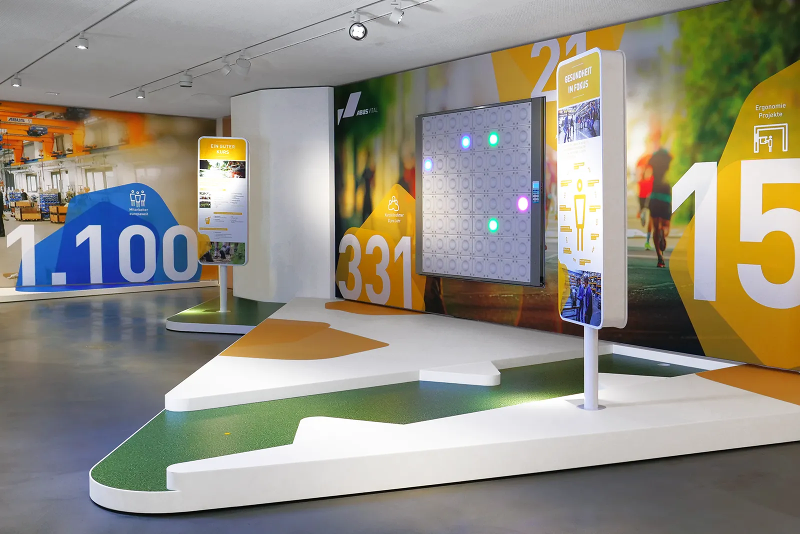 Blick in den VITAL-Raum bei Abus-Kransysteme Showroom mit interaktiver Lichtwand, Infostelen und Wandgrafiken zu Gesundheit und Ergonomie