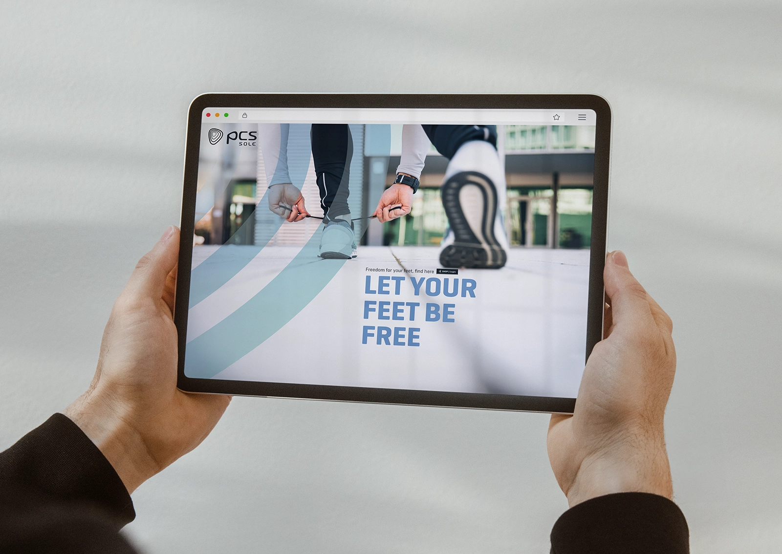 Person hält ein Tablet in der Hand, auf dem die Startseite der PCS Sole Website zu sehen ist – zur Veranschaulichung des neuen Rebrandings.