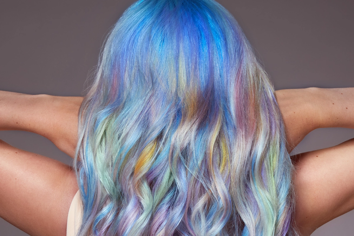 Close-up of the back of a woman's head with long hair in a gradient from blue to rainbow - created as part of the Hair Haus photo shoot.
