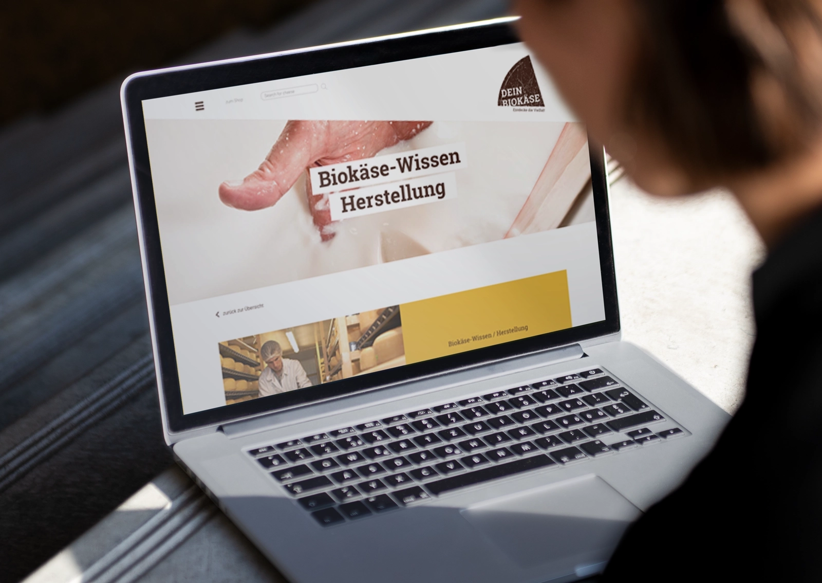 Ansicht eines Laptops mit der Website des DEIN BIOKÄSE-Shops – konzipiert für Digital Natives, die ihre Biokäse-Auswahl online bestellen.