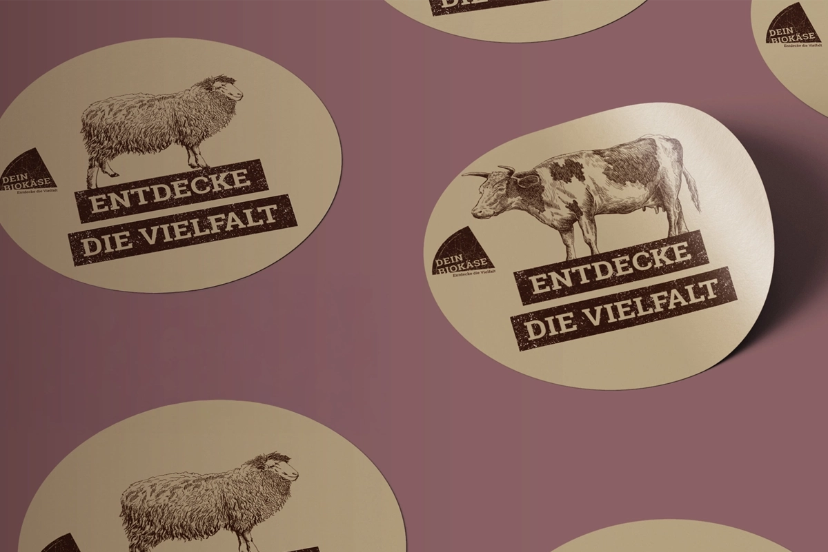 Runde Aufkleber von DEIN BIOKÄSE mit goldenen Akzenten und Logo – gestaltet als Branding-Element.