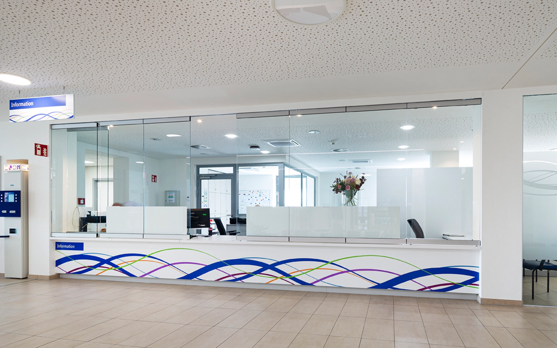 Innenaufnahme der Anmeldung im Hauptgebäude der Städtische Kliniken Mönchengladbach mit integriertem Leitsystem an der Informationstheke. Gestaltung und Umsetzung durch die R211-Agentur.