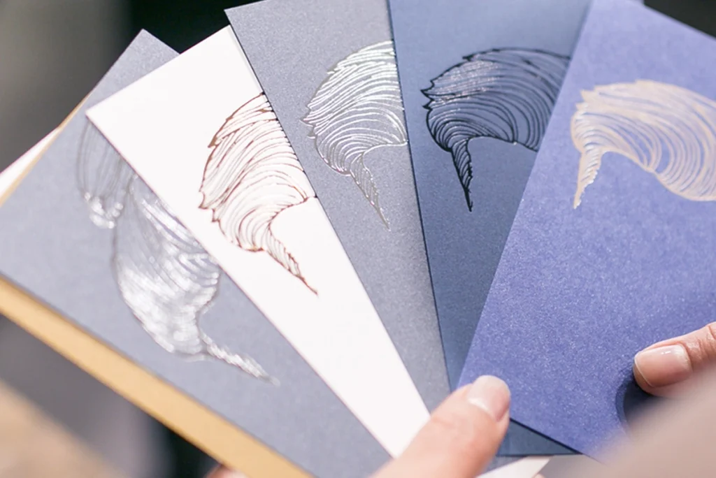 Eventbesucher hält verschiedene Papiermuster in der Hand und begutachtet die Haptik. Aufnahme vom Paper Playground Event von Freytag & Petersen, visuell gestaltet von der R211-Agentur.