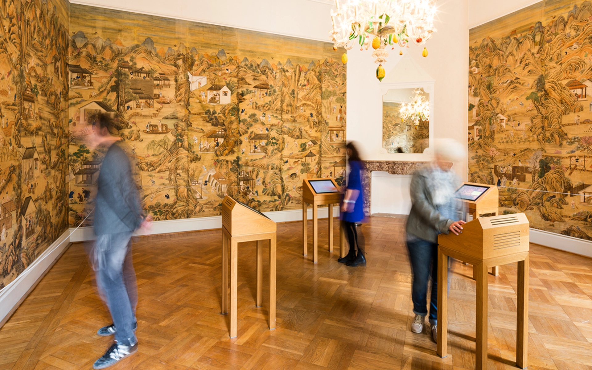 Mehrere Besucher bedienen das User Interface für die Medien-Installation der Chinesischen Seidentapete als interaktive Station der Stiftung Schloss Dyck